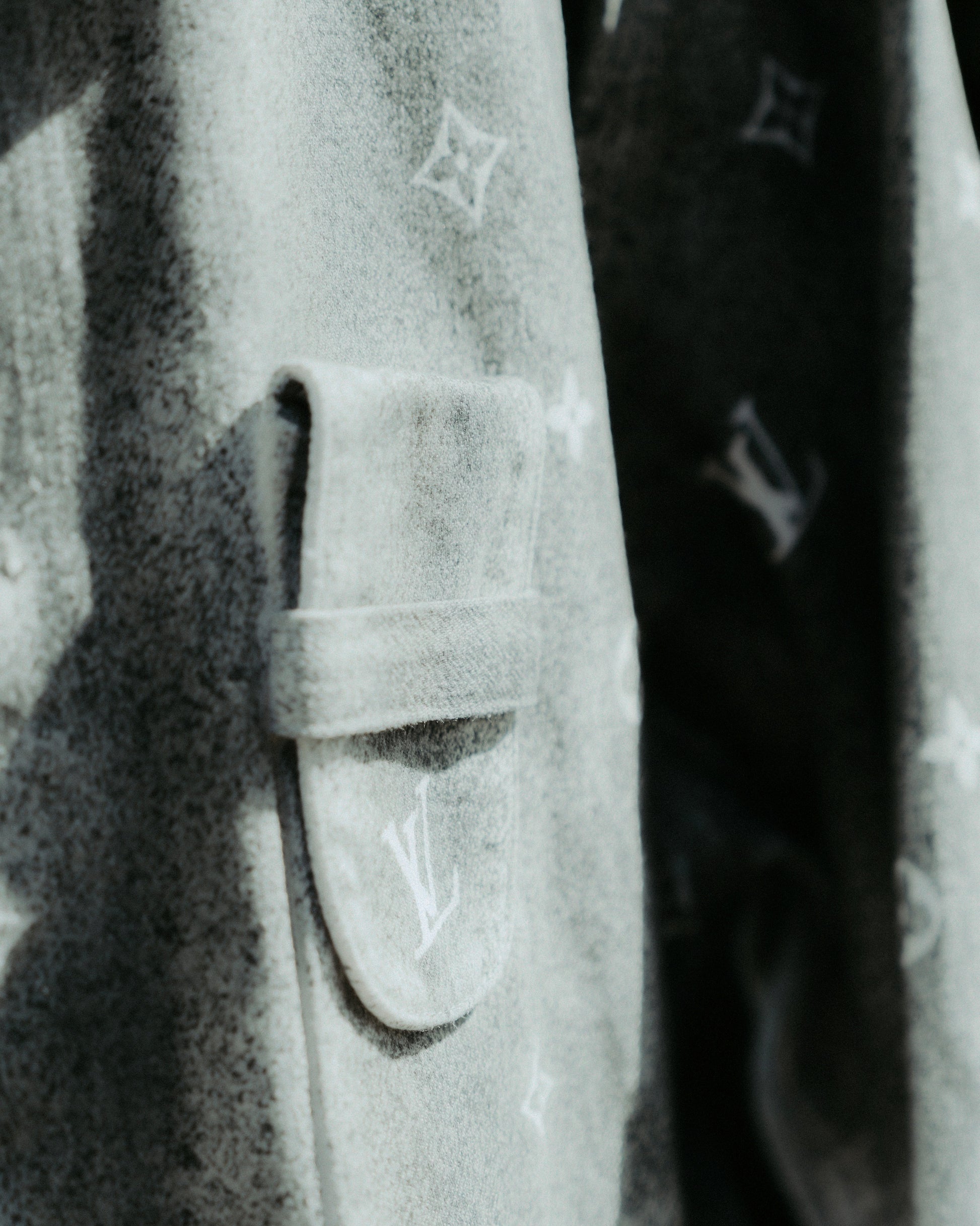 Close-up of a grey textured Louis Vuitton shirt with a flap pocket featuring a subtle monogram design.