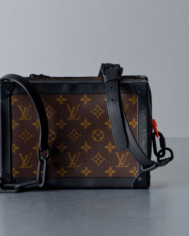 Designer Louis Vuitton handbag with monogram pattern on a gray background
