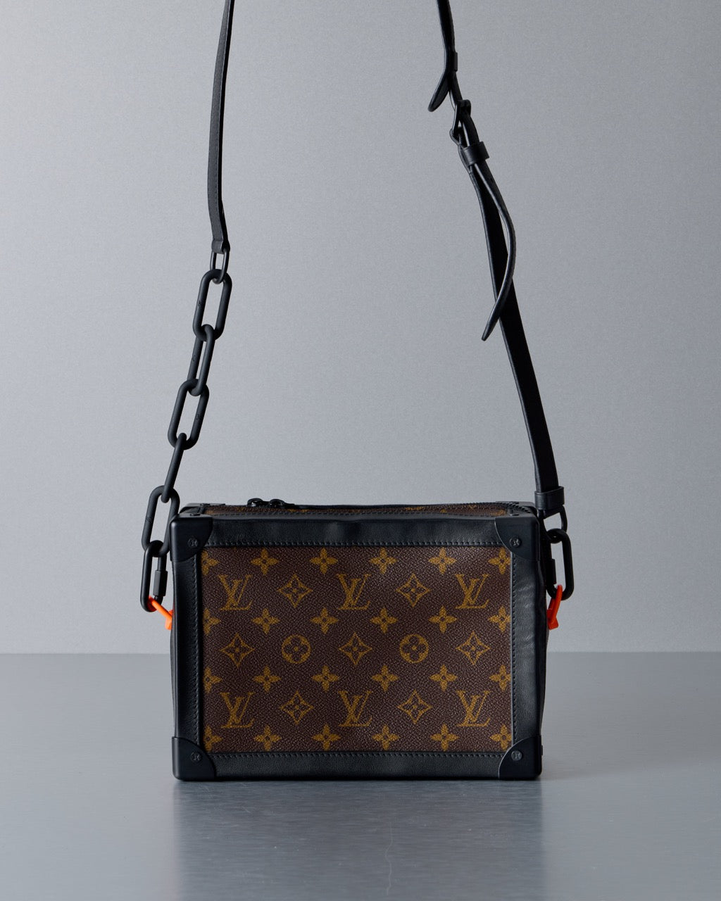 Designer Louis Vuitton handbag with monogram pattern on a gray background