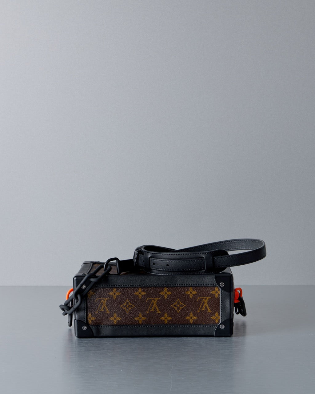 Designer Louis Vuitton handbag with monogram pattern on a gray background
