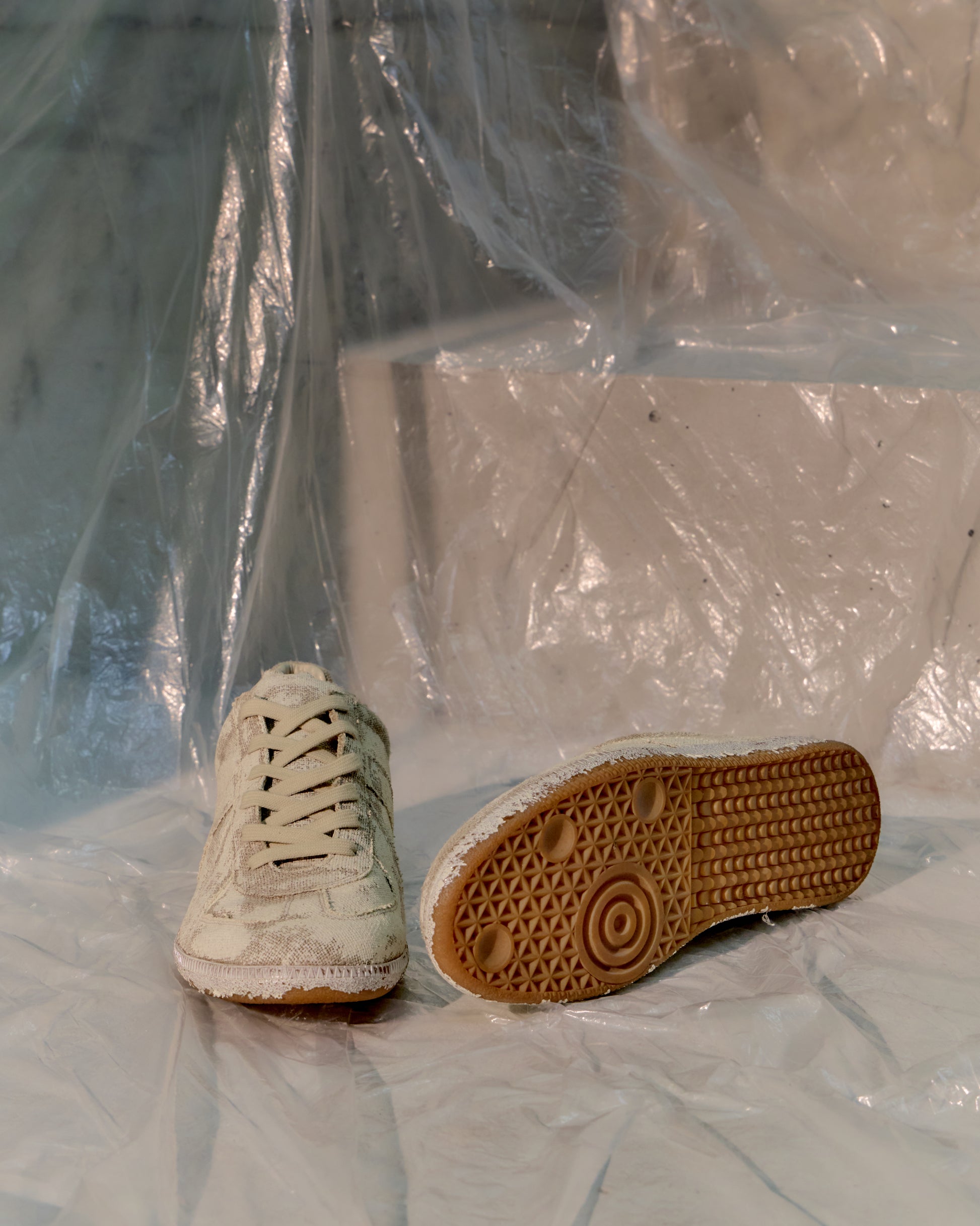 Pair of worn Maison Margiela GAT sneakers on a plastic surface with a transparent background