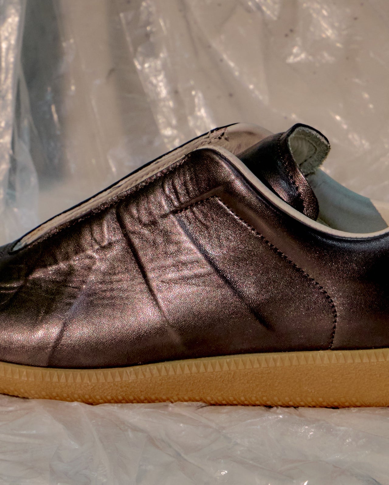Brown Maison Margiela shoe with a yellow sole on a transparent plastic sheet