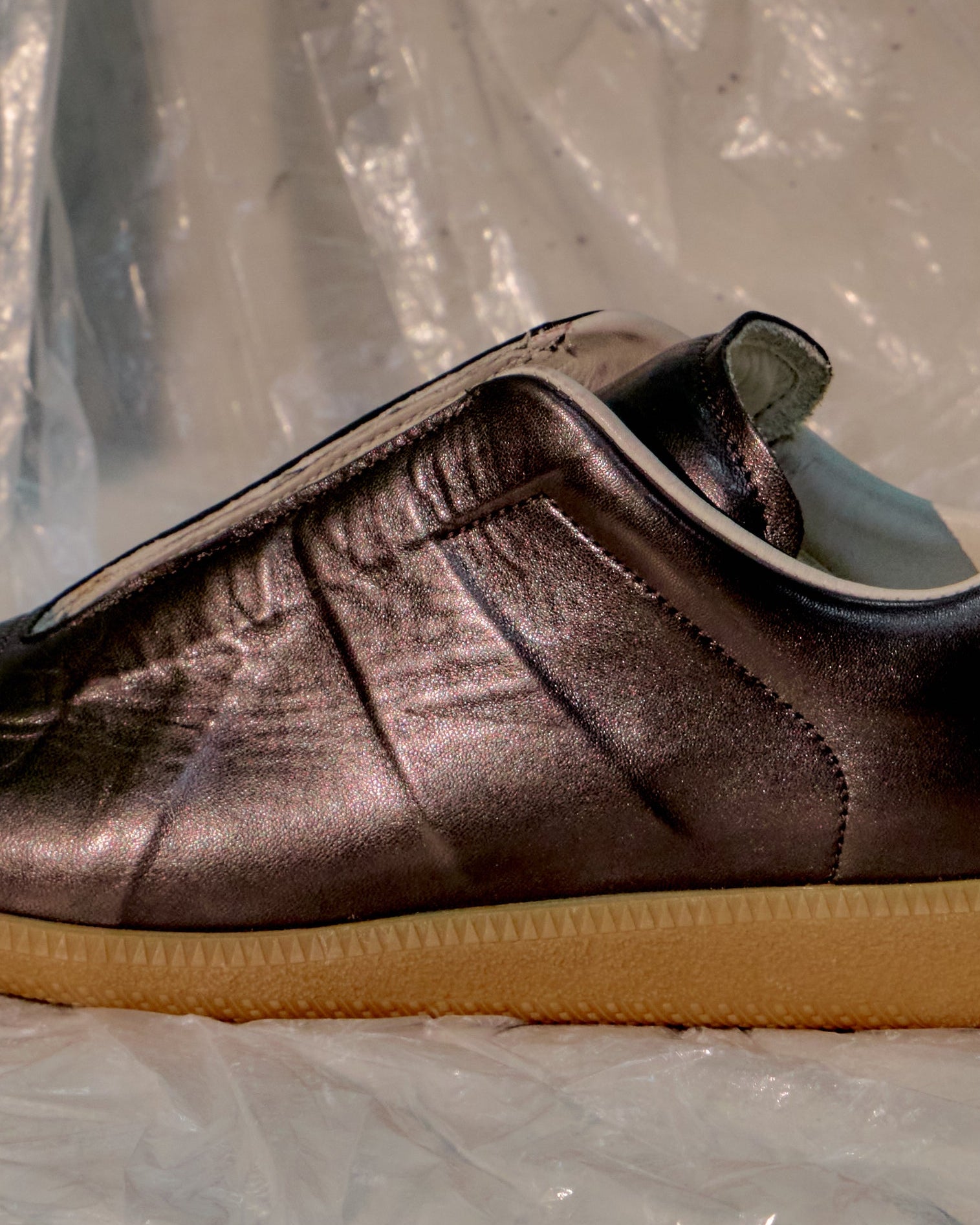 Brown metallic Maison Margiela sneaker with a yellow sole on a reflective surface