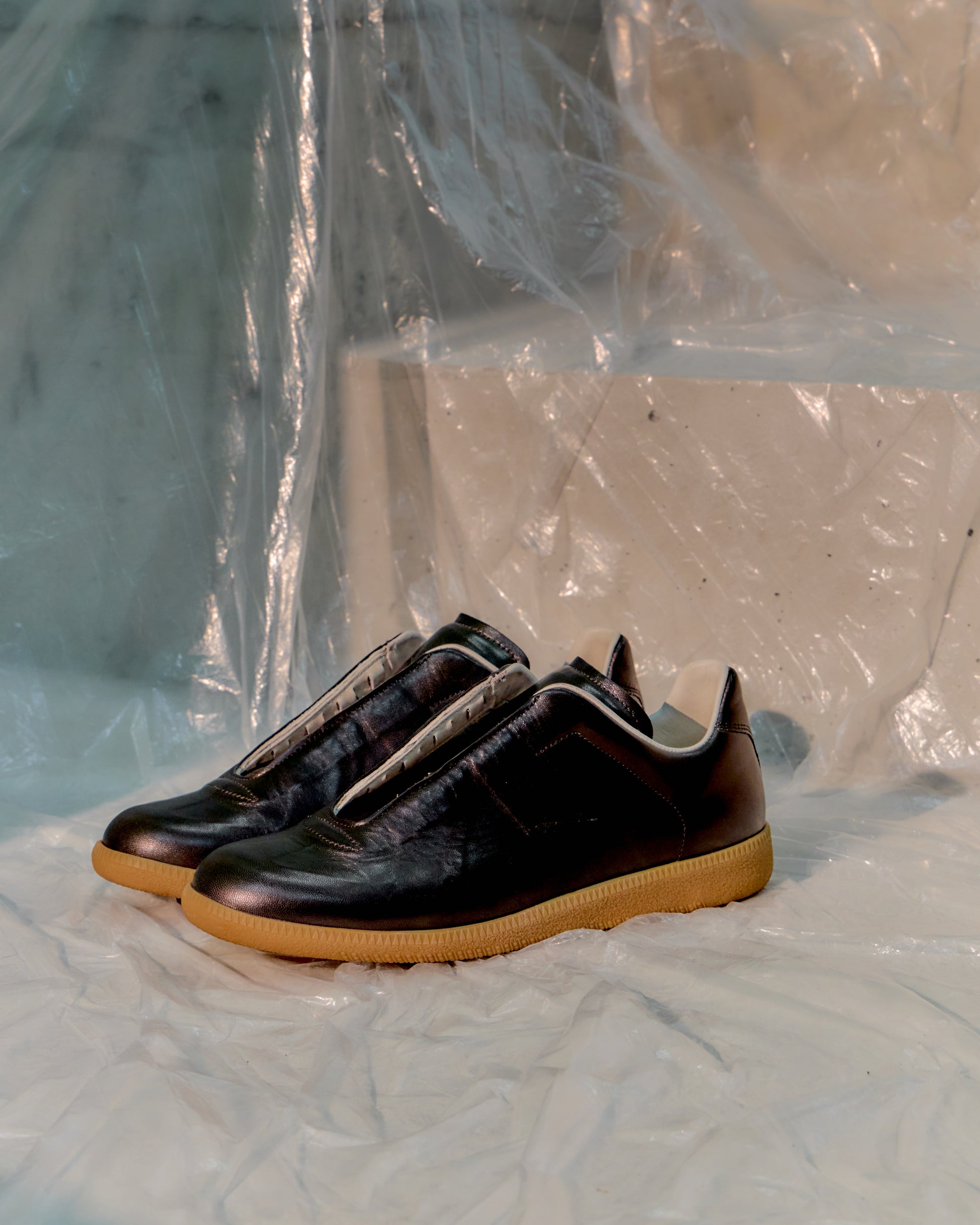 Pair of black Maison Margiela shoes with brown soles on a white surface