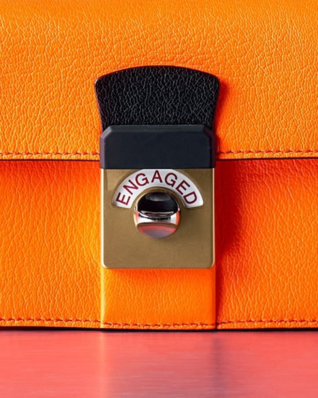 Orange Maison Margiela handbag with a yellow strap on a gray background