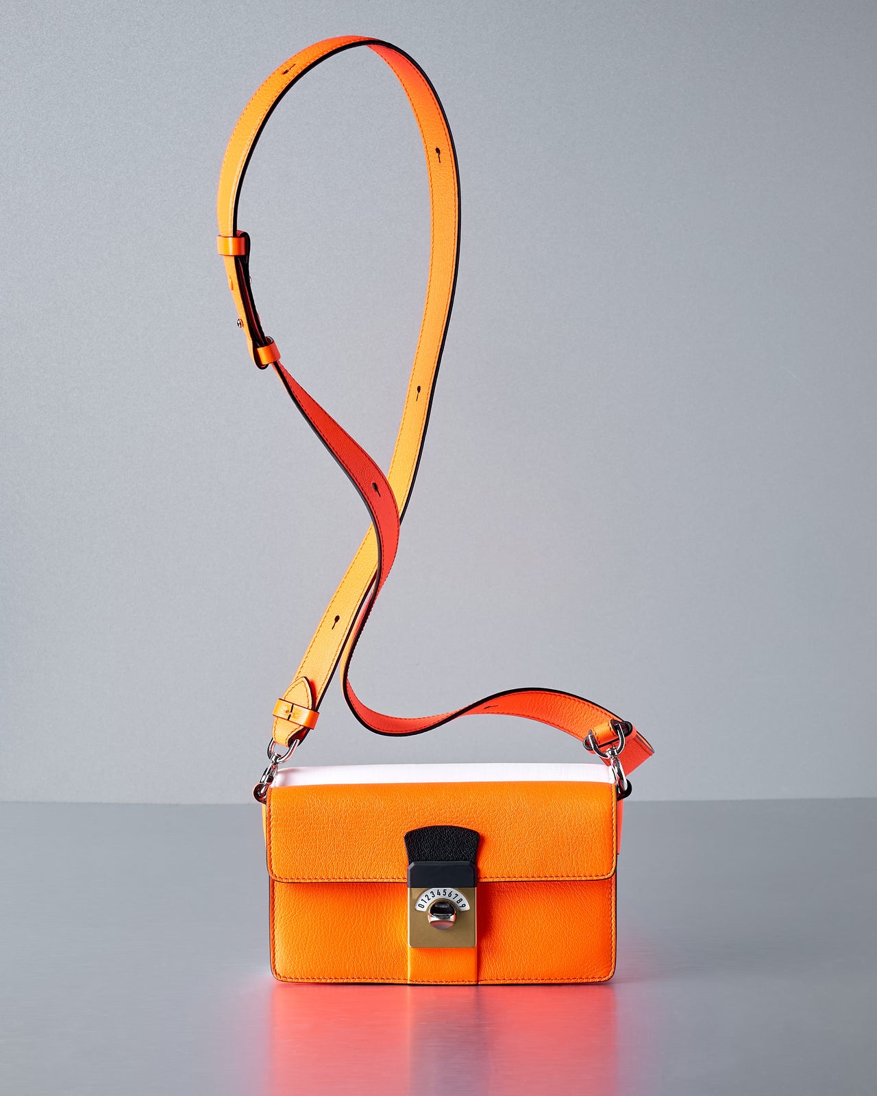 Orange Maison Margiela handbag with a yellow strap on a gray background