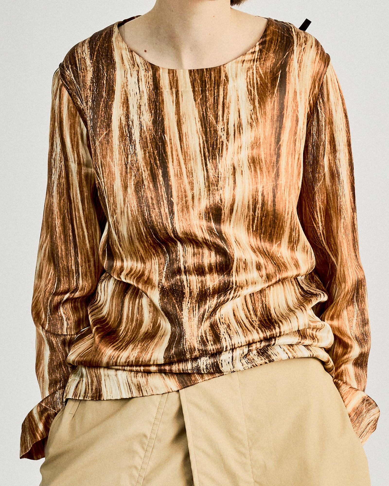 Person in a hair print Maison Margiela patterned long-sleeve shirt and beige pants, standing casually with hands in pockets against a plain background.