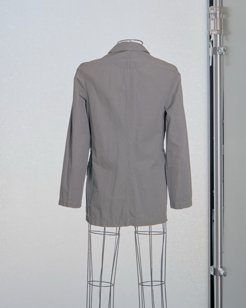 Gray Maison Margiela blazer on a mannequin against a plain background