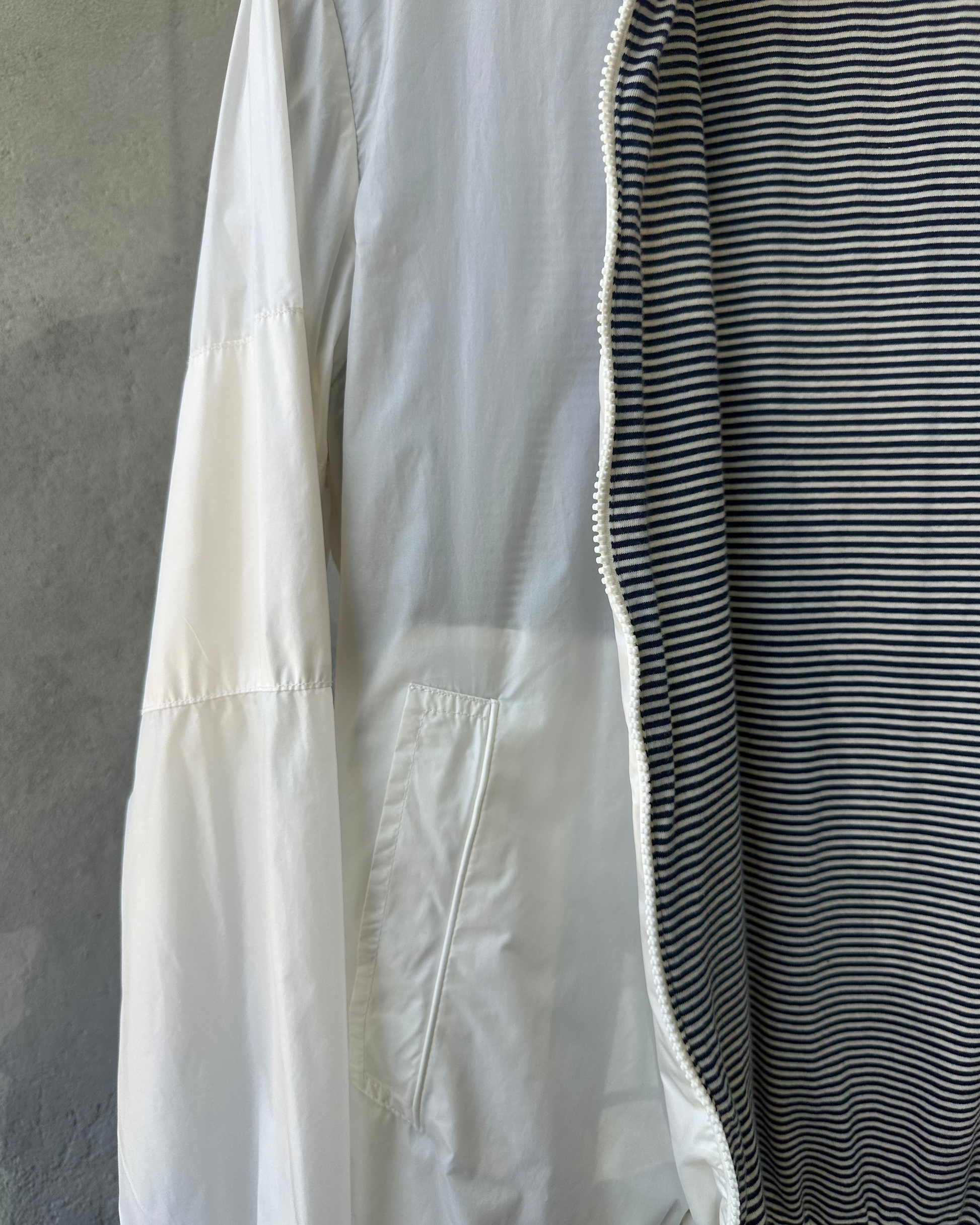 White Maison Margiela jacket with black and white striped lining against a gray background
