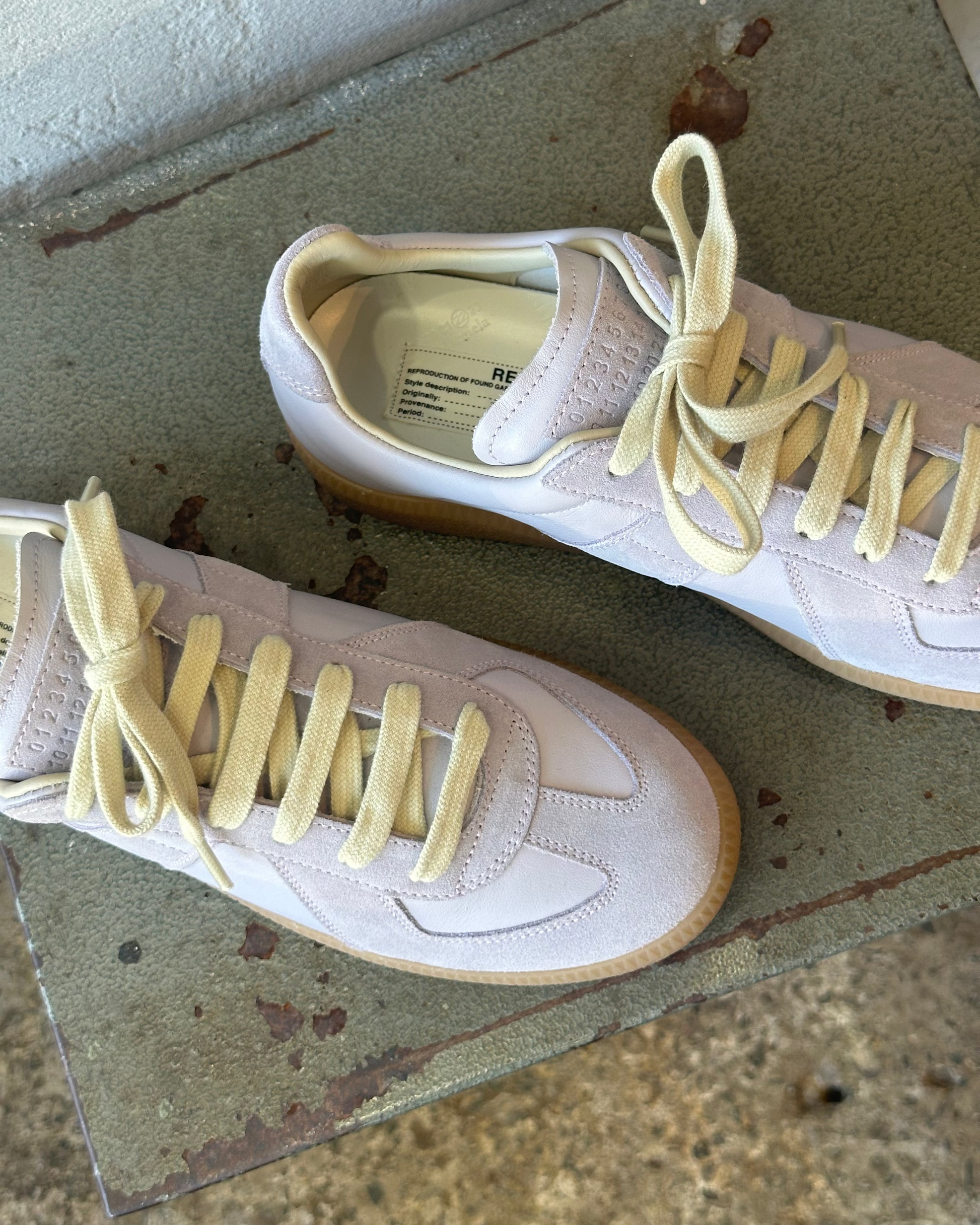 Purple Maison Margiela sneakers with yellow laces on a concrete surface