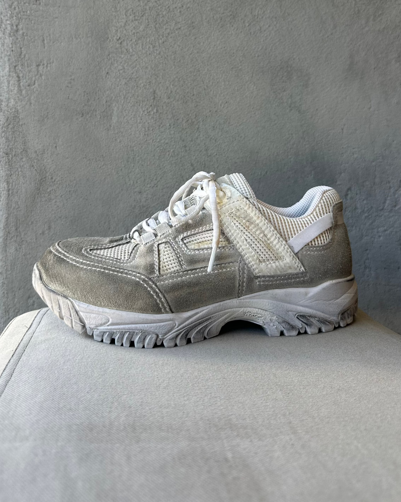 Gray Maison Margiela athletic shoe on a gray surface with a gray background