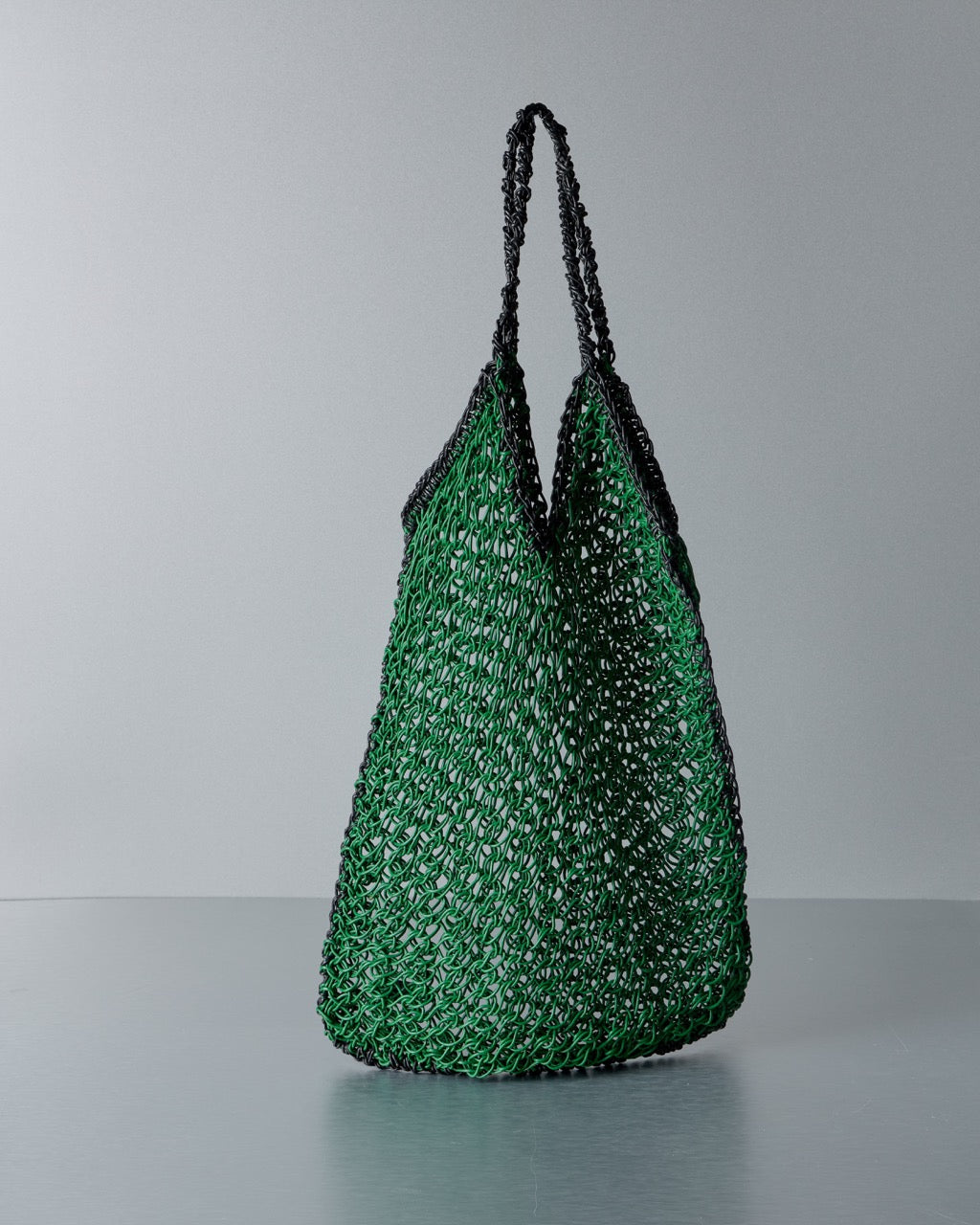 Green woven Max Mara bag with black handles on a gray background