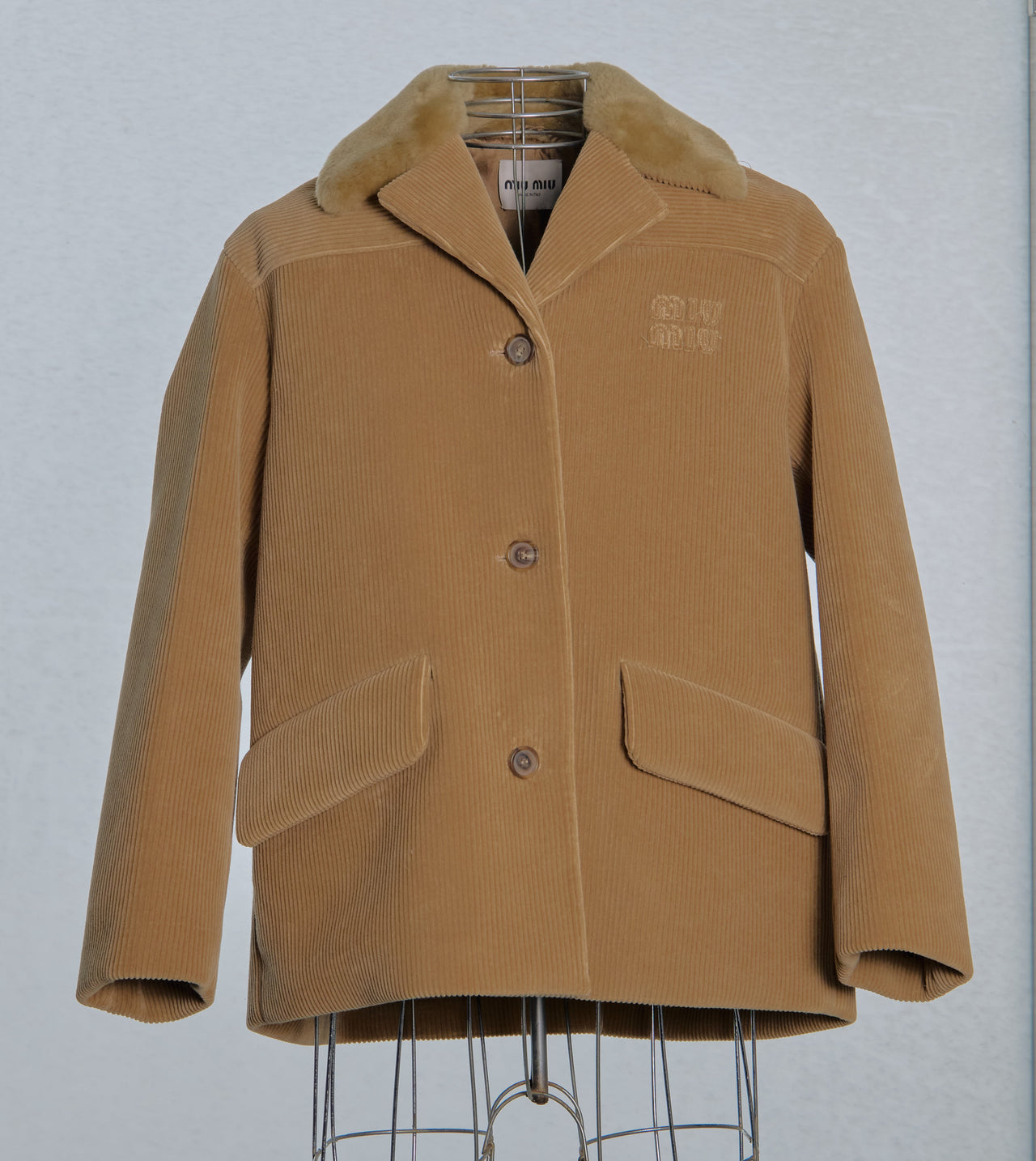 Brown corduroy Miu Miu jacket with fur collar on a gray background