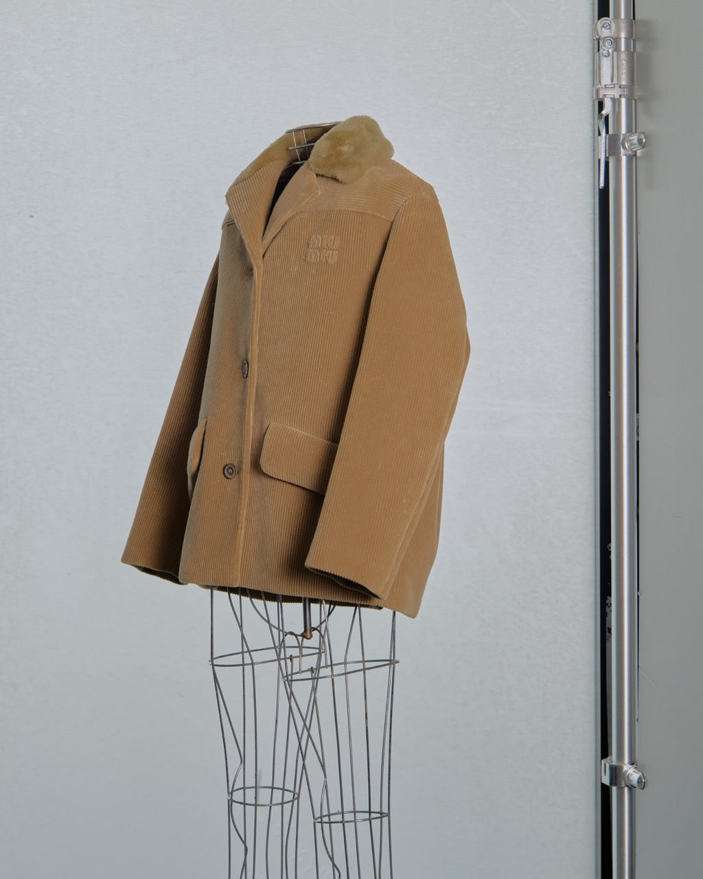 Brown corduroy Miu Miu jacket with fur collar on a gray background