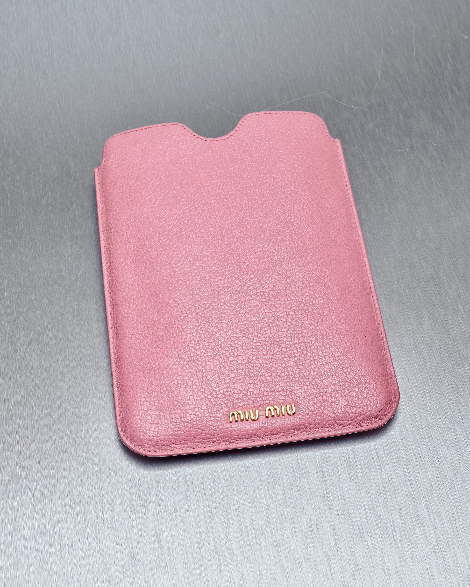 A pink Miu Miu leather iPad mini sleeve with gold studded branding and tonal stitching.