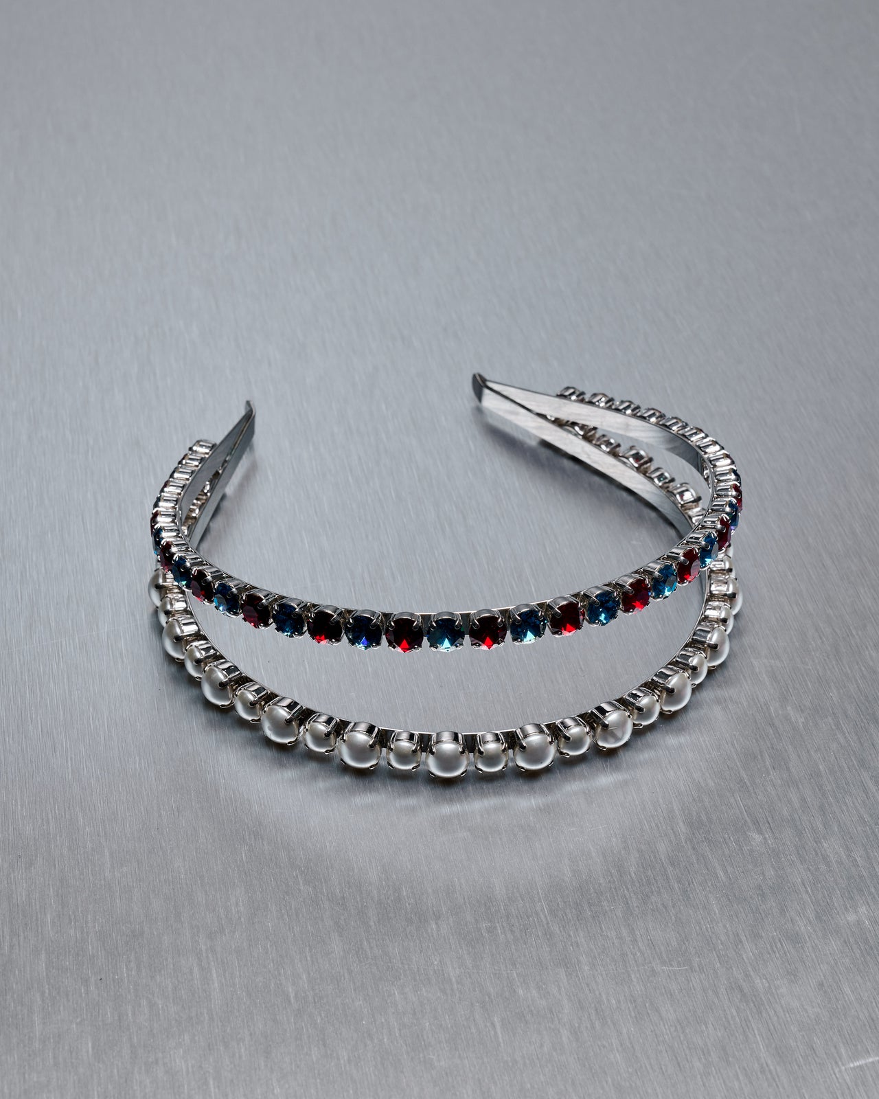 Person with tattoos wearing a Miu Miu double headband sitting in a room with green wallpaper and books on the floor.