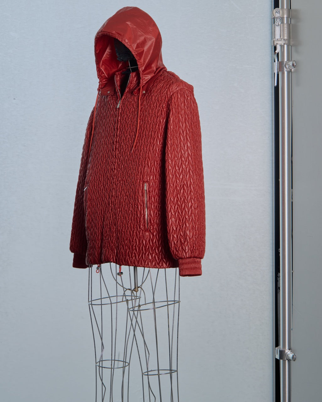 Red knitted Miu Miu puffer jacket on a mannequin against a white background