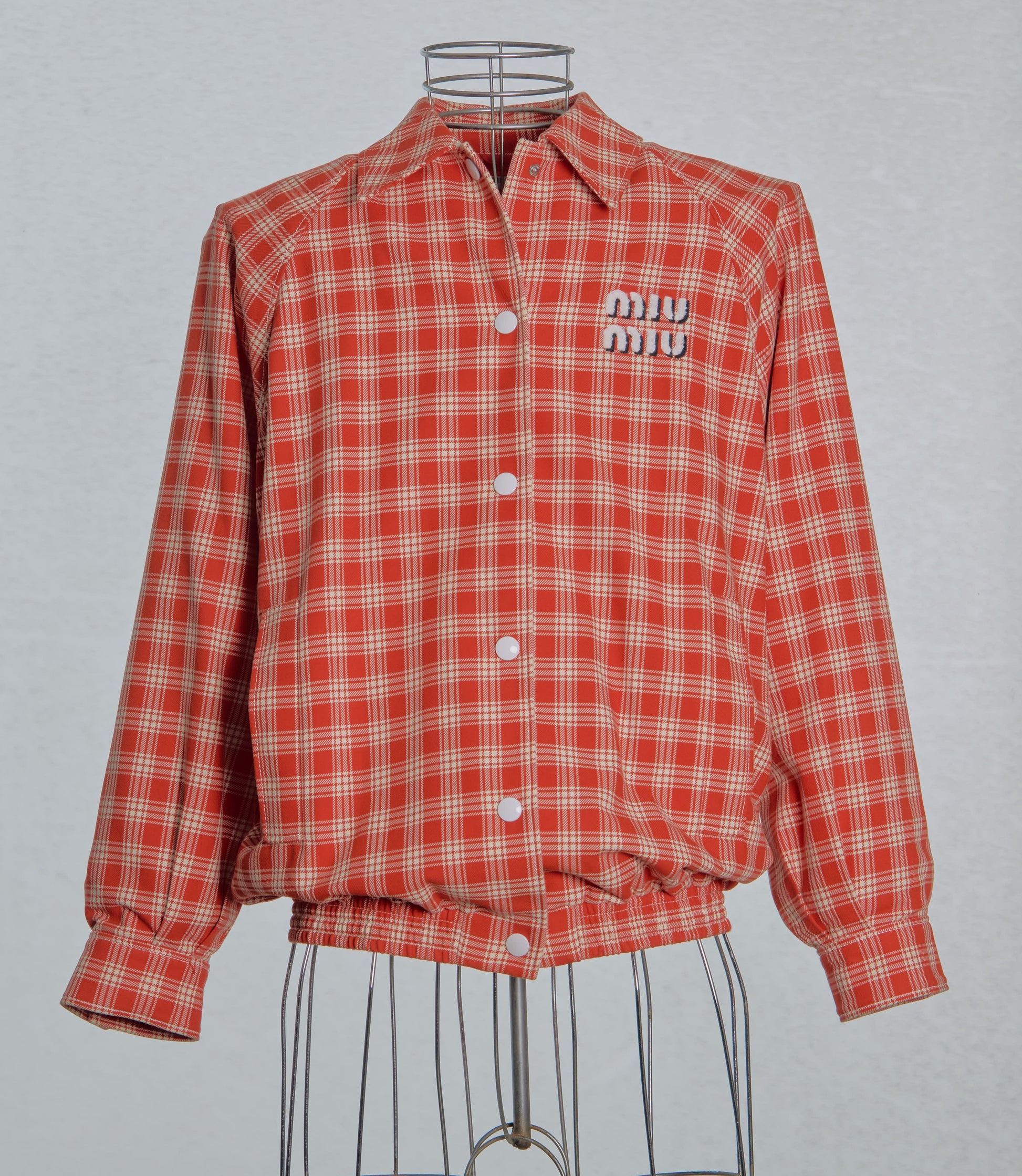 Red plaid Miu Miu jacket with brand logo on a gray background