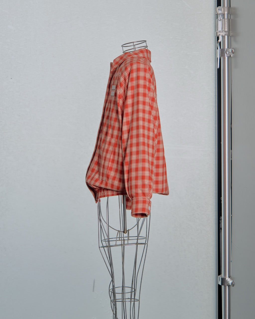 Red and white checkered Miu Miu bomber jacket on a mannequin against a gray background