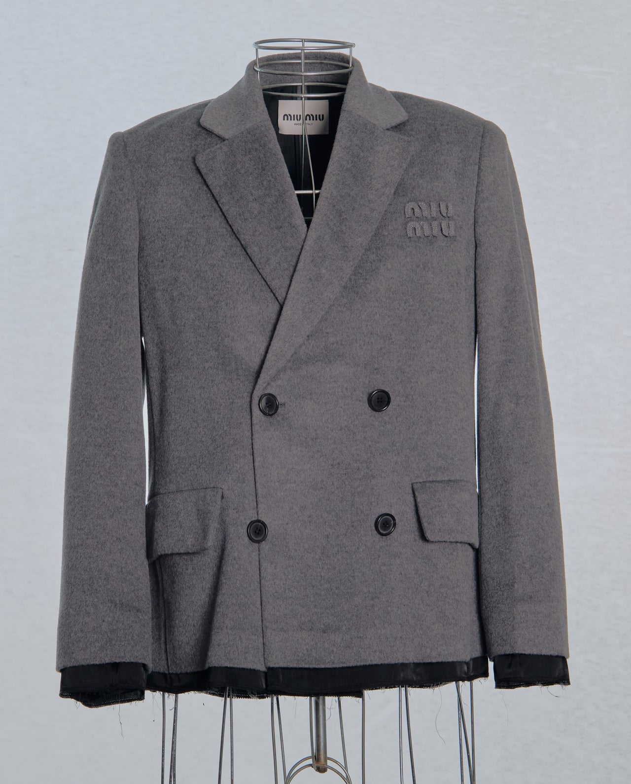 Gray double-breasted  Miu Miu jacket on a mannequin against a light gray background