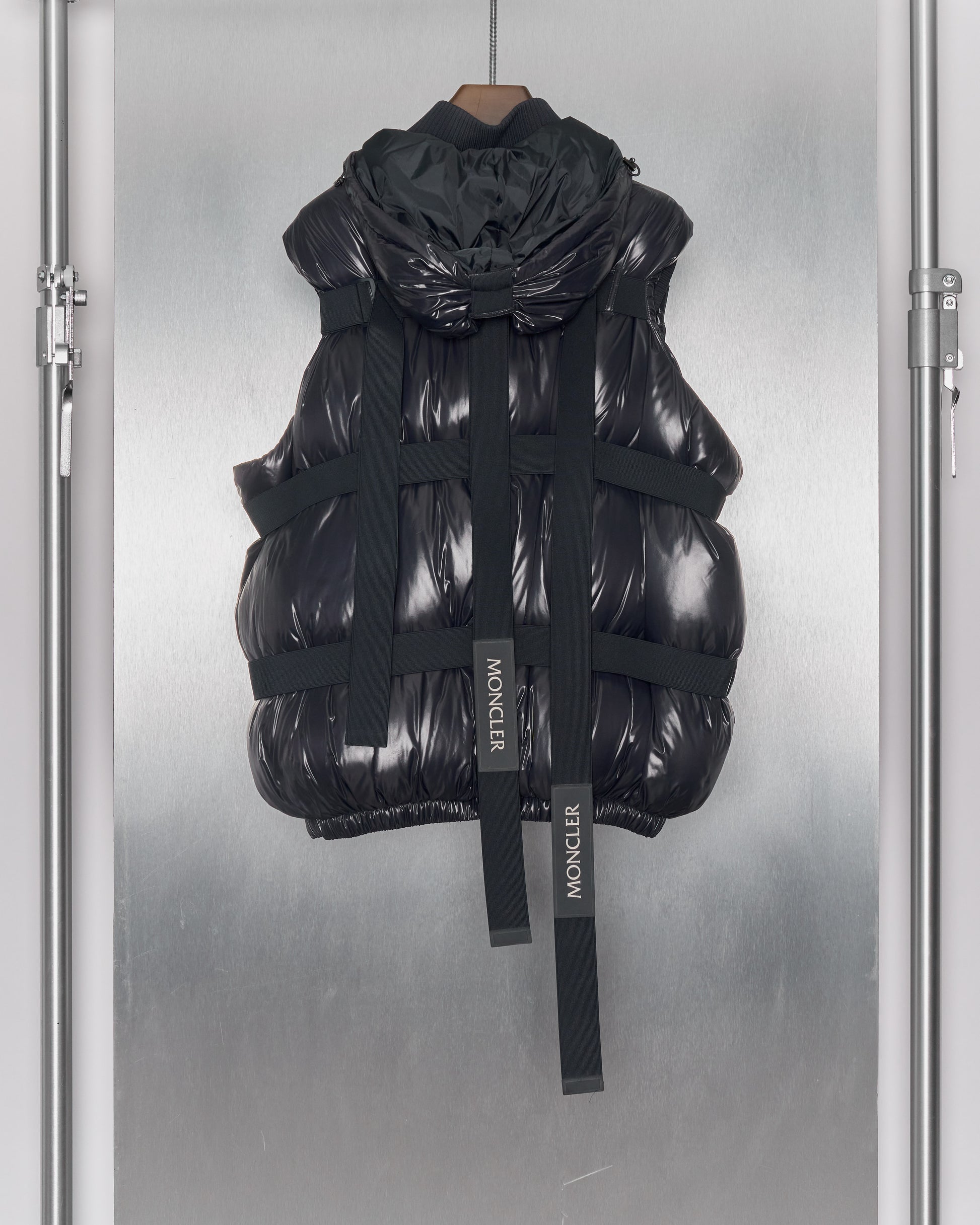 Reverse of a black Moncler x Craig Green hooded gilet with elastic straps, ribbed collar and double-zip front.