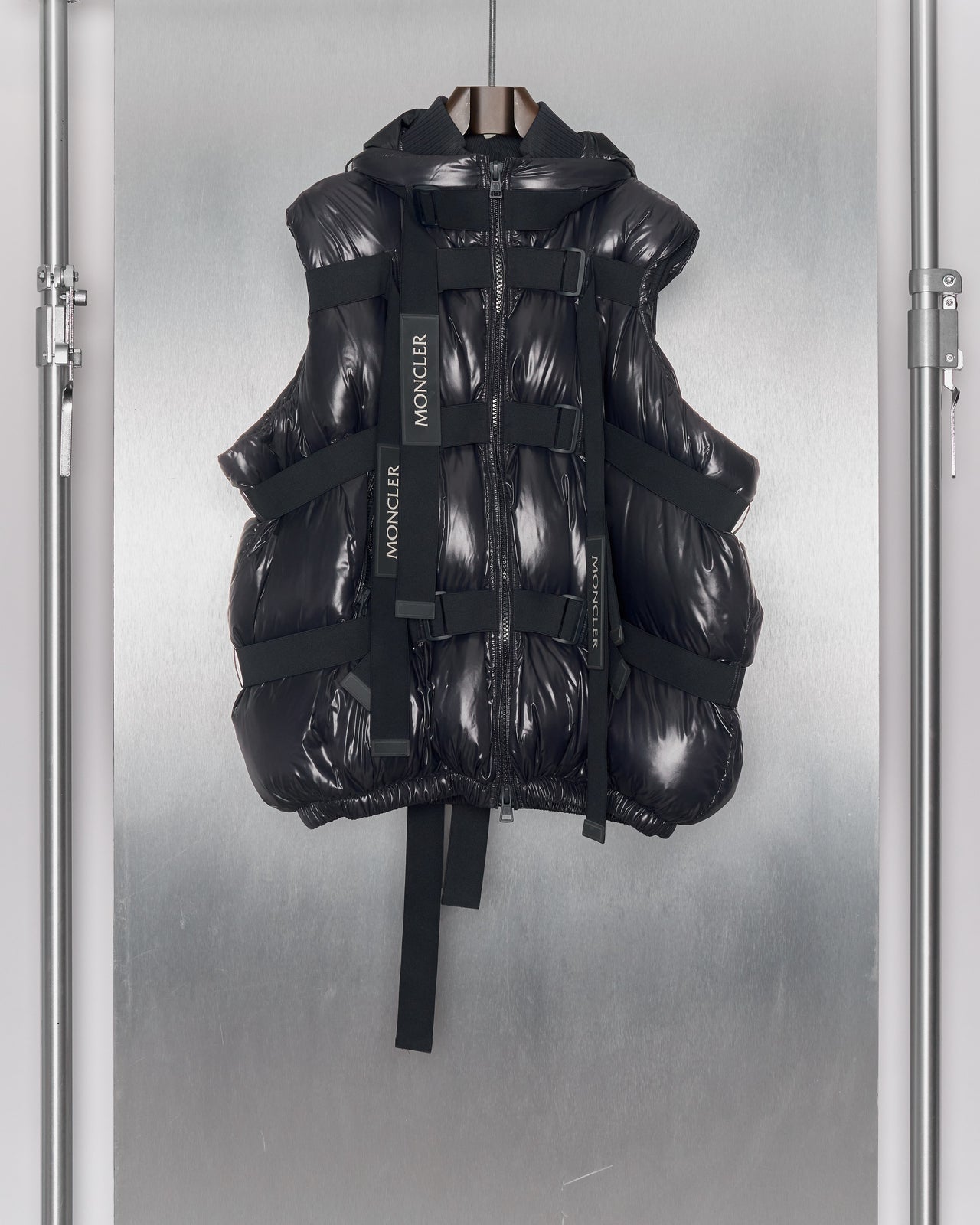 Person in futuristic, padded Moncler x Craig Green black outfit with a hood and layered puffy sections. Stands against a neutral background.