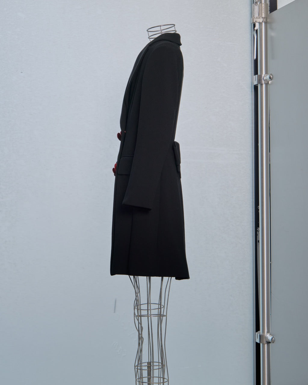 Black Moschino coat on a mannequin against a light gray wall