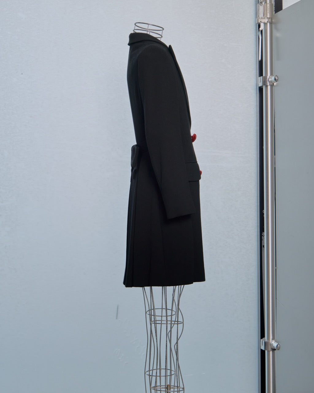 Black Moschino coat on a mannequin against a light blue wall
