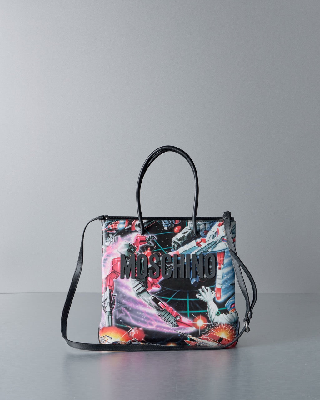 Multicoloured handbag with 'Moschino' branding on a gray background