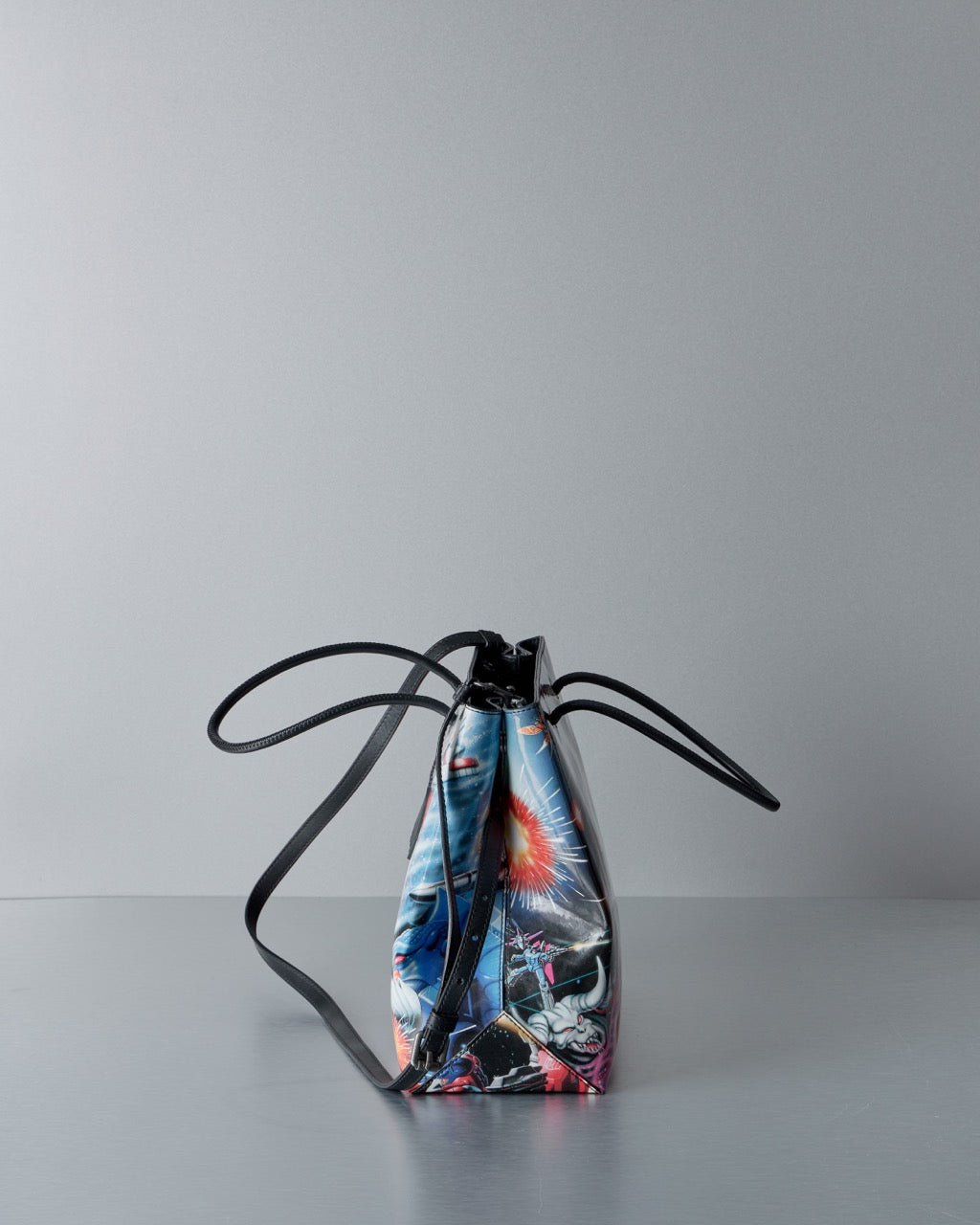 Colourful Moschino bag with black handles on a gray background