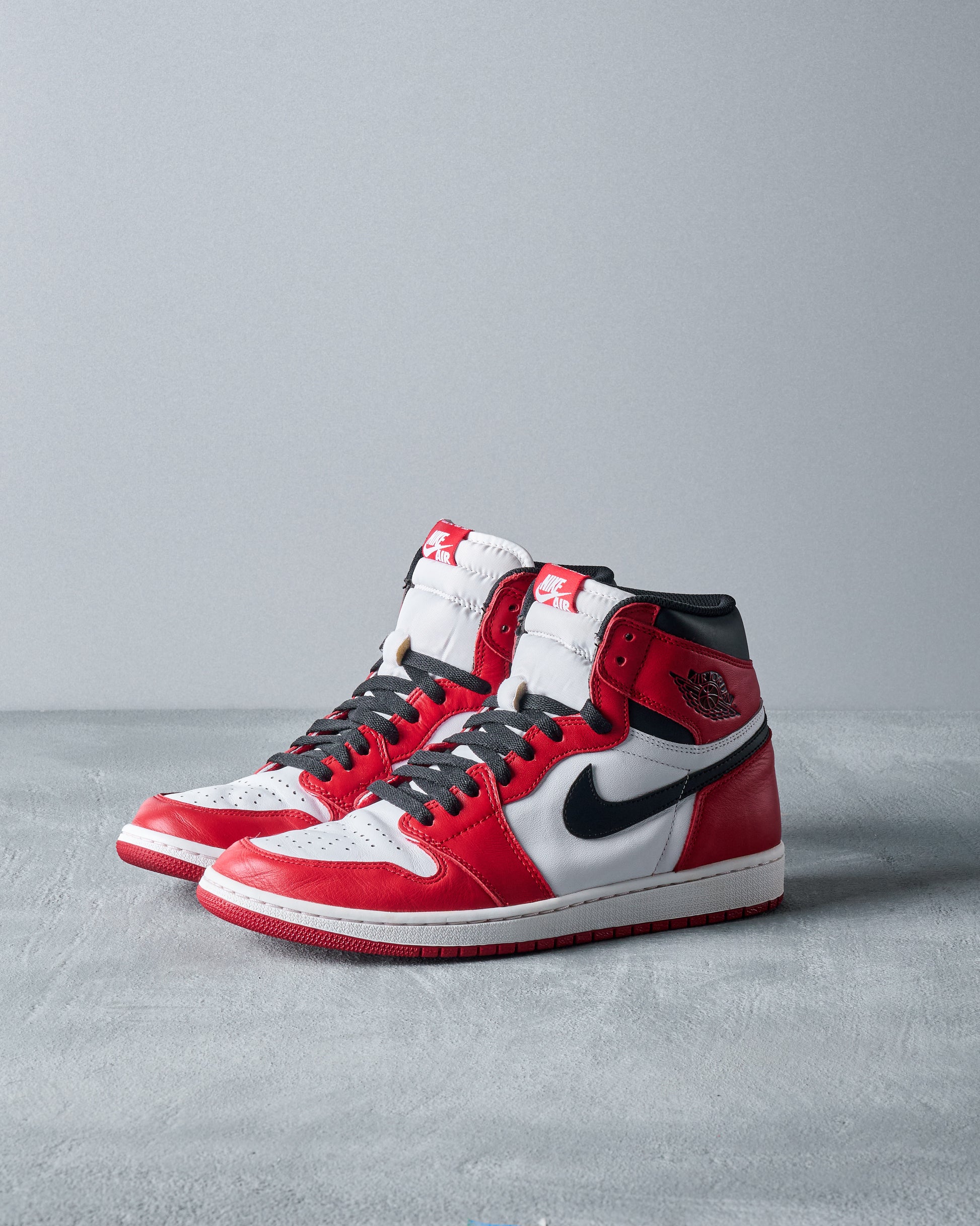 Red, black, and white high-top sneakers with a Nike swoosh on the side, displayed against a neutral background. Sporty and stylish design.