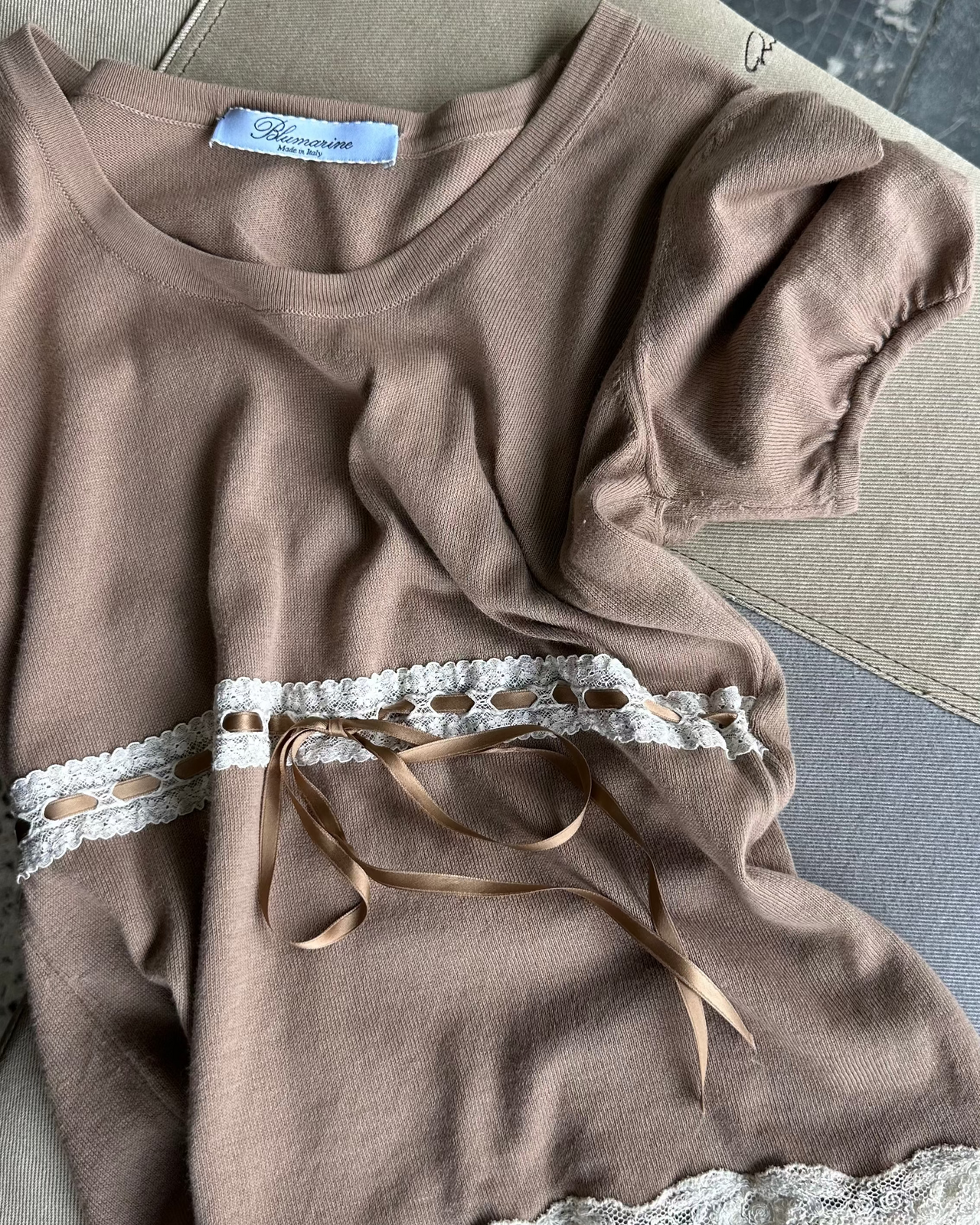 Brown Blumarine top with lace details on a textured surface
