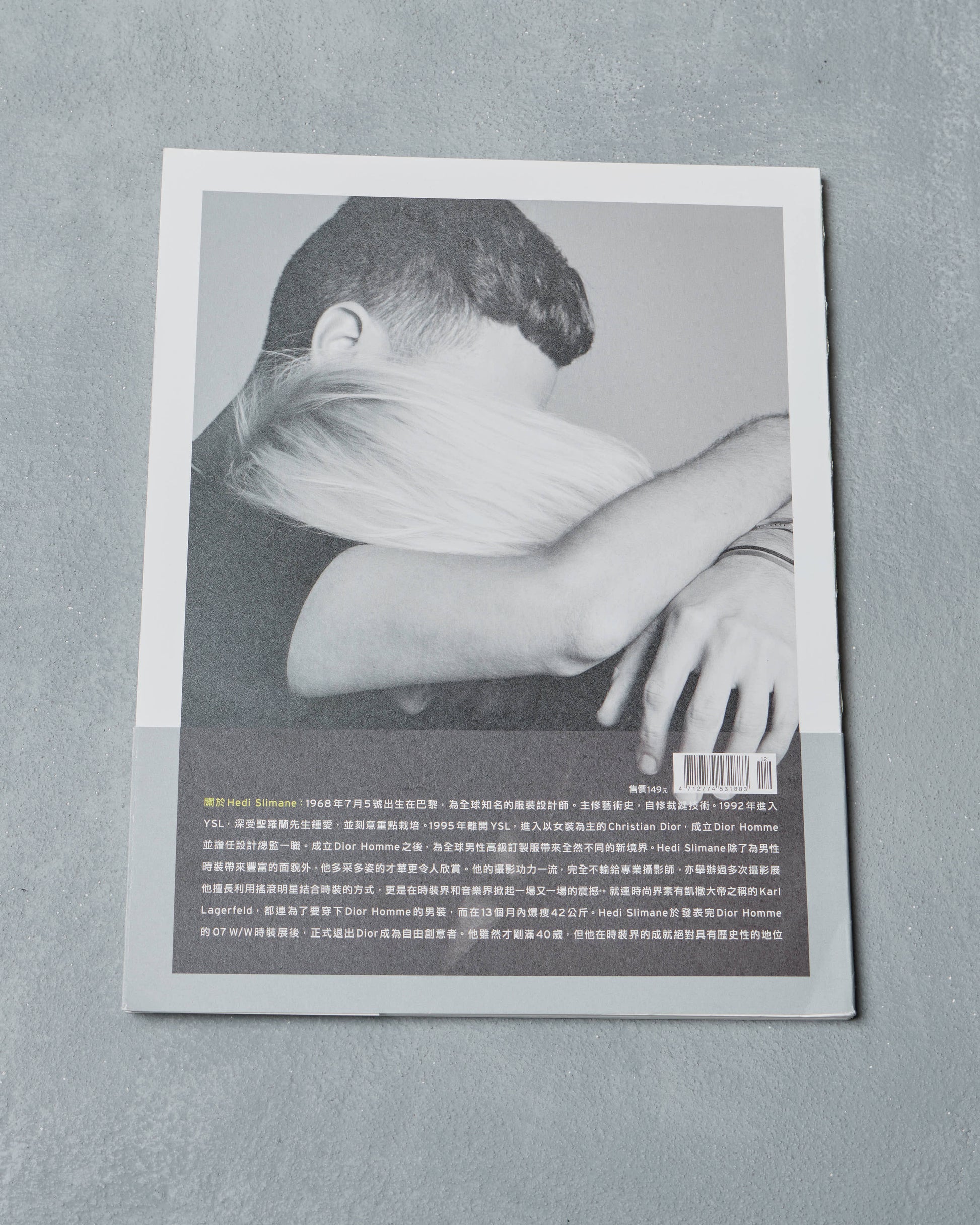Black and white photo of a person on a the back of a Ppaper Magazine sits on a gray background