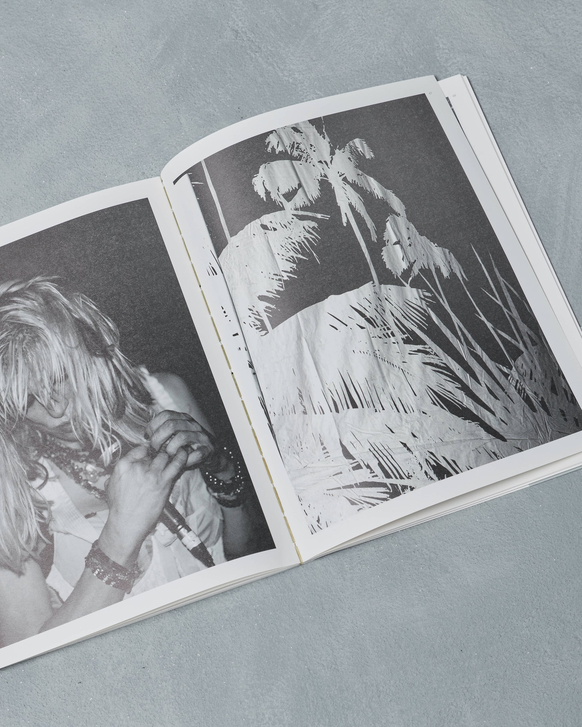Open Ppaper Magazine with black and white photographs of a person and natural scenery on a gray surface