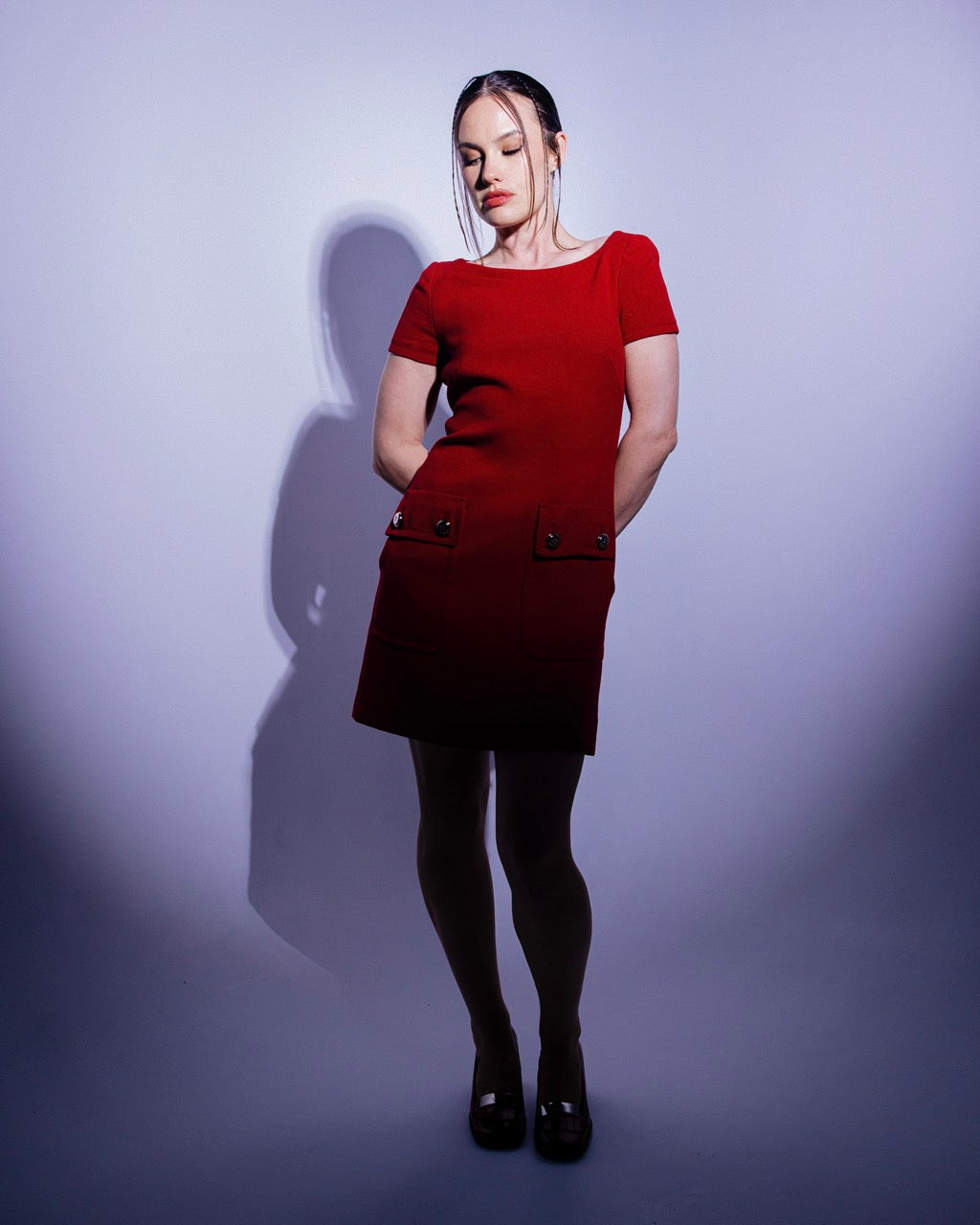 Woman wearing a red Prada shift dress against a purple background
