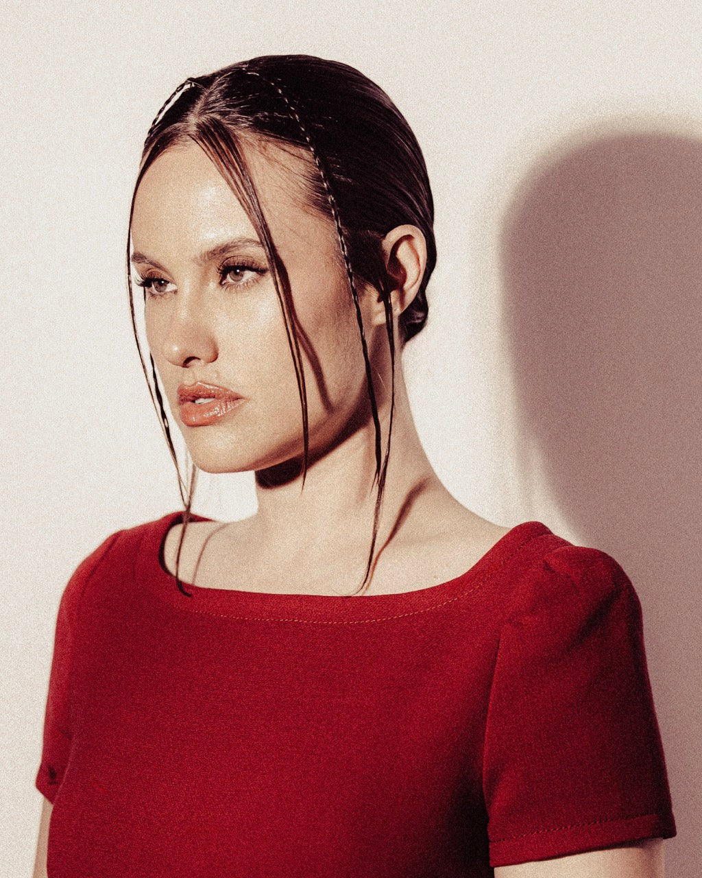 Woman wearing a red Prada shift dress with a plain background