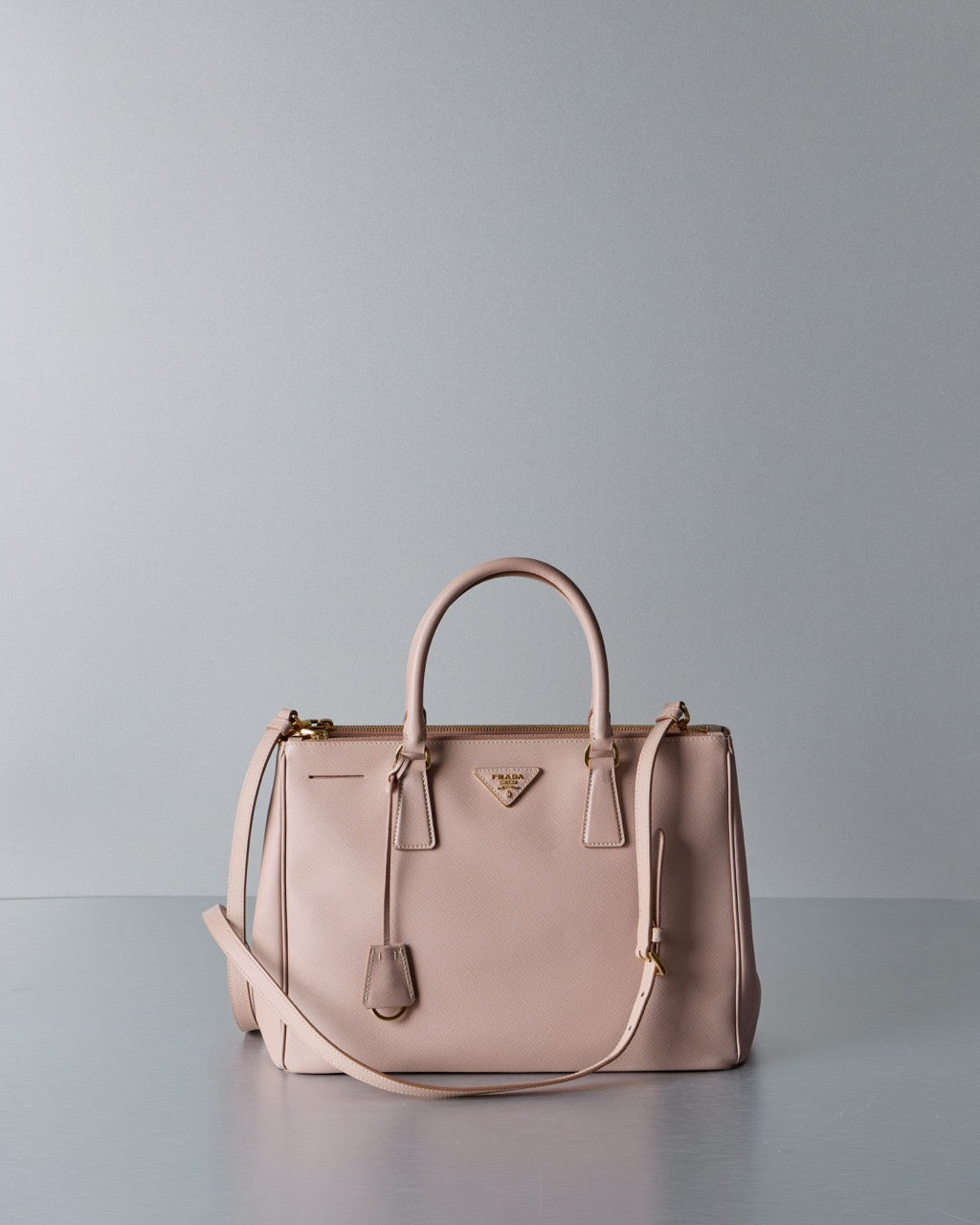 Pink Prada handbag with a visible brand logo on a gray background