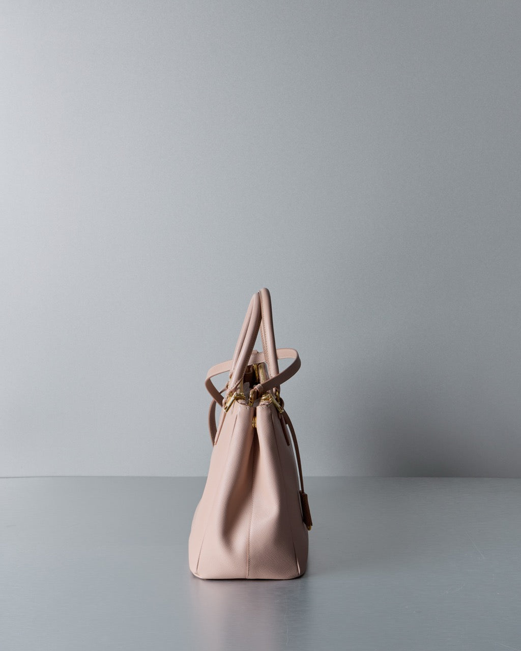 Pink Prada handbag on a gray surface with a light gray background