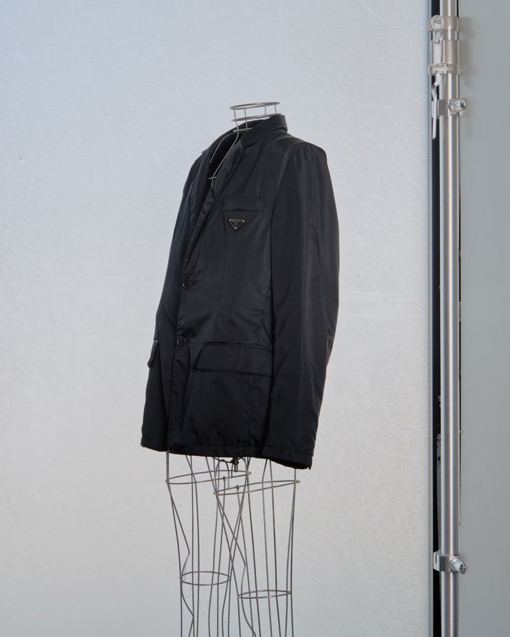 Black nylon Prada jacket on a mannequin against a light gray background