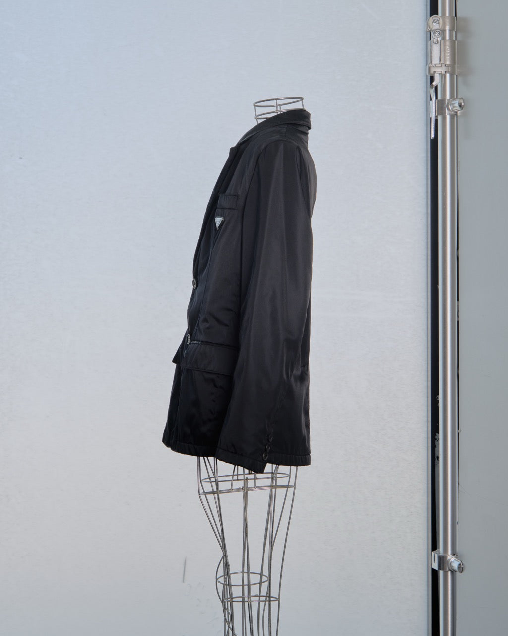 Black nylon Prada jacket on a mannequin against a light gray background