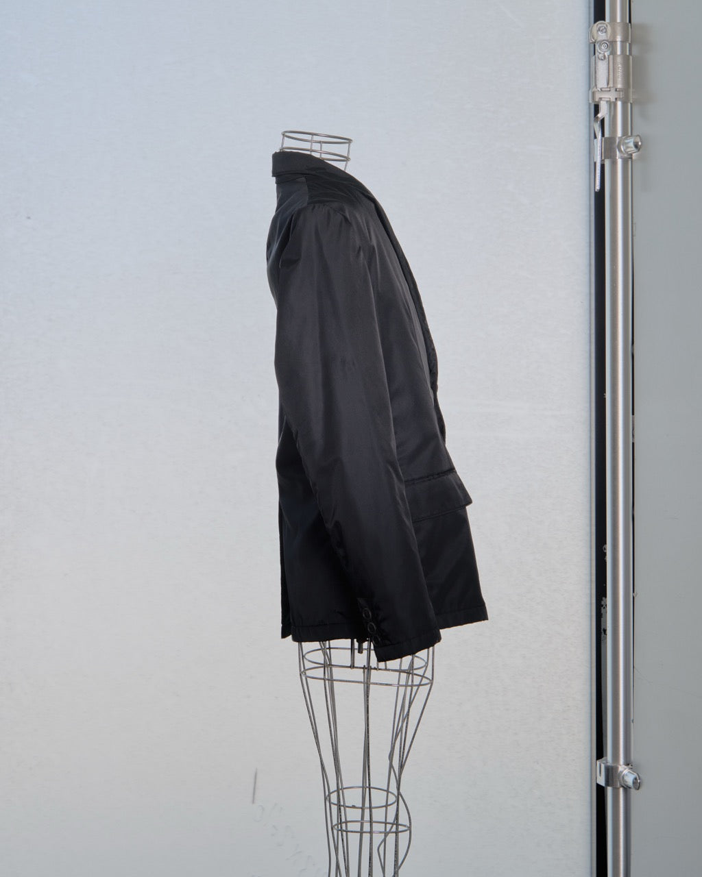 Black nylon Prada coat on a mannequin against a plain background