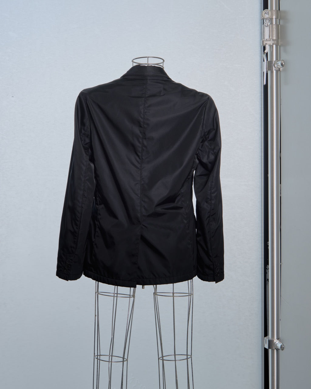 Black Prada jacket on a mannequin against a plain background