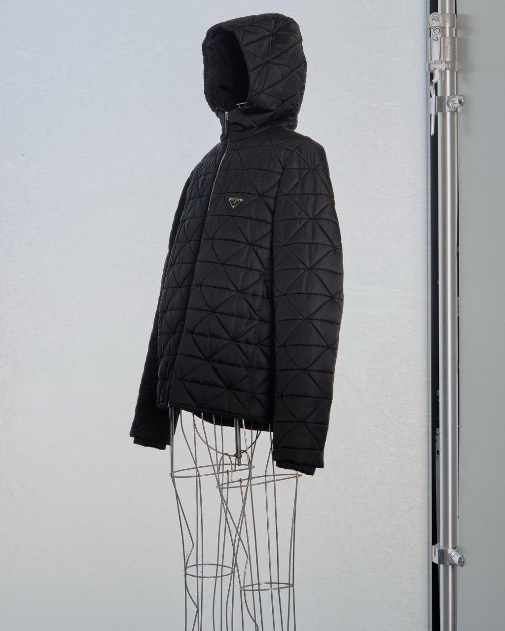 Black quilted Prada jacket on a mannequin against a light gray background