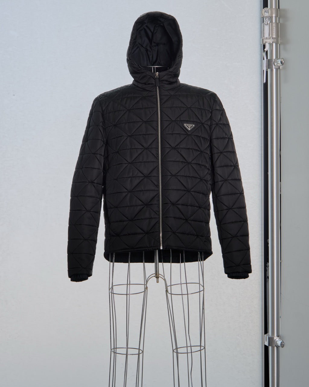 Black quilted Prada jacket on a mannequin against a light gray background