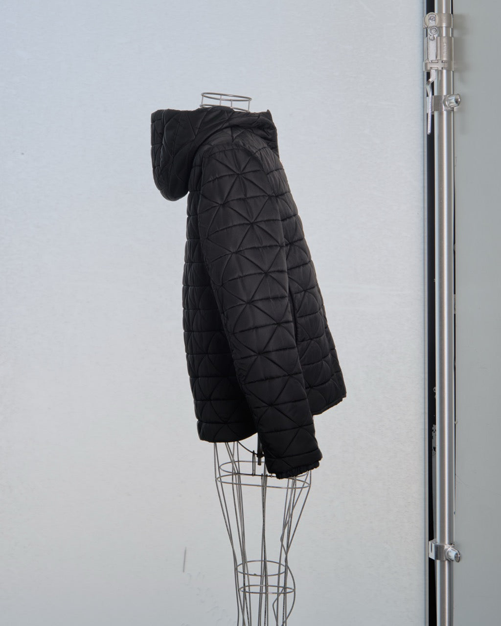 Black quilted Prada jacket on a mannequin against a light gray background