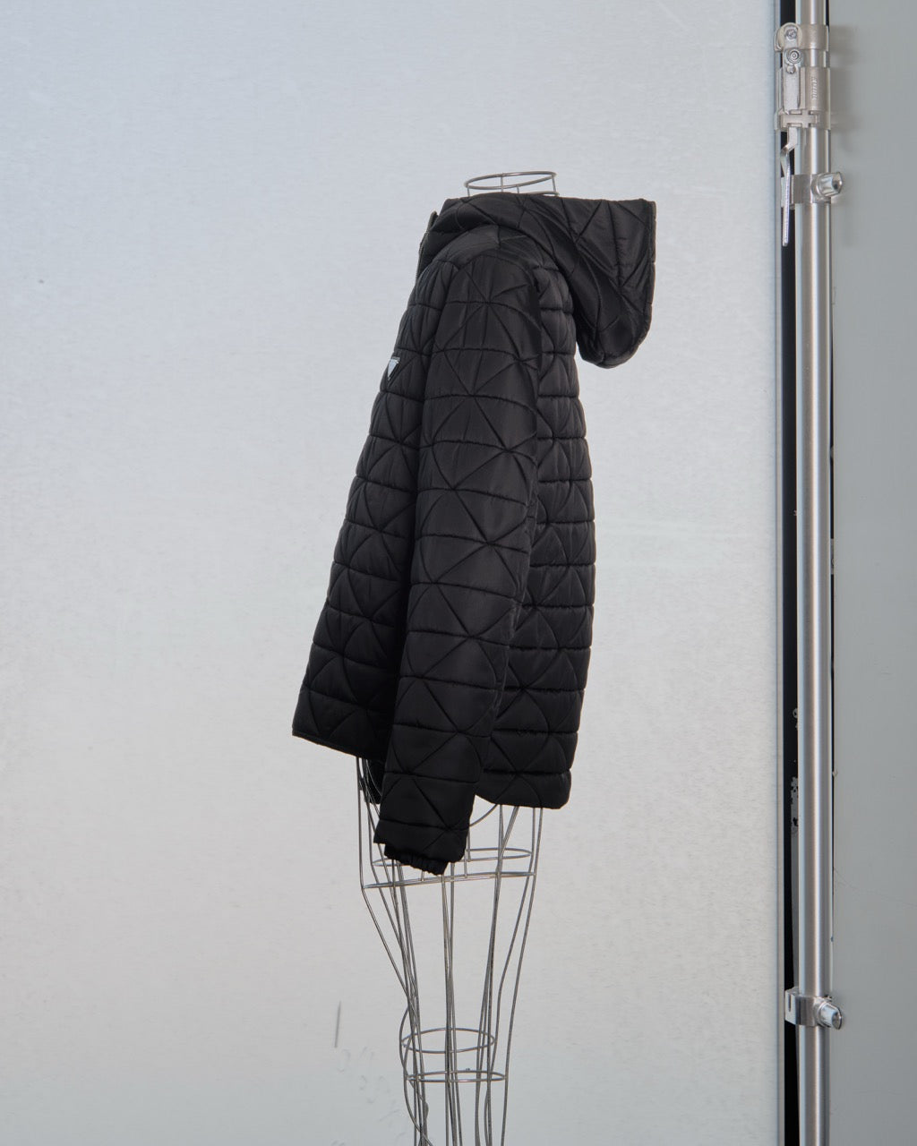 Black quilted Prada jacket on a mannequin against a white background