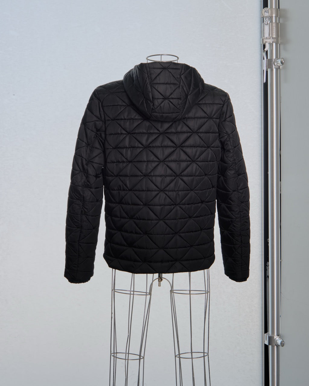 Black quilted Prada jacket on a mannequin against a light gray background