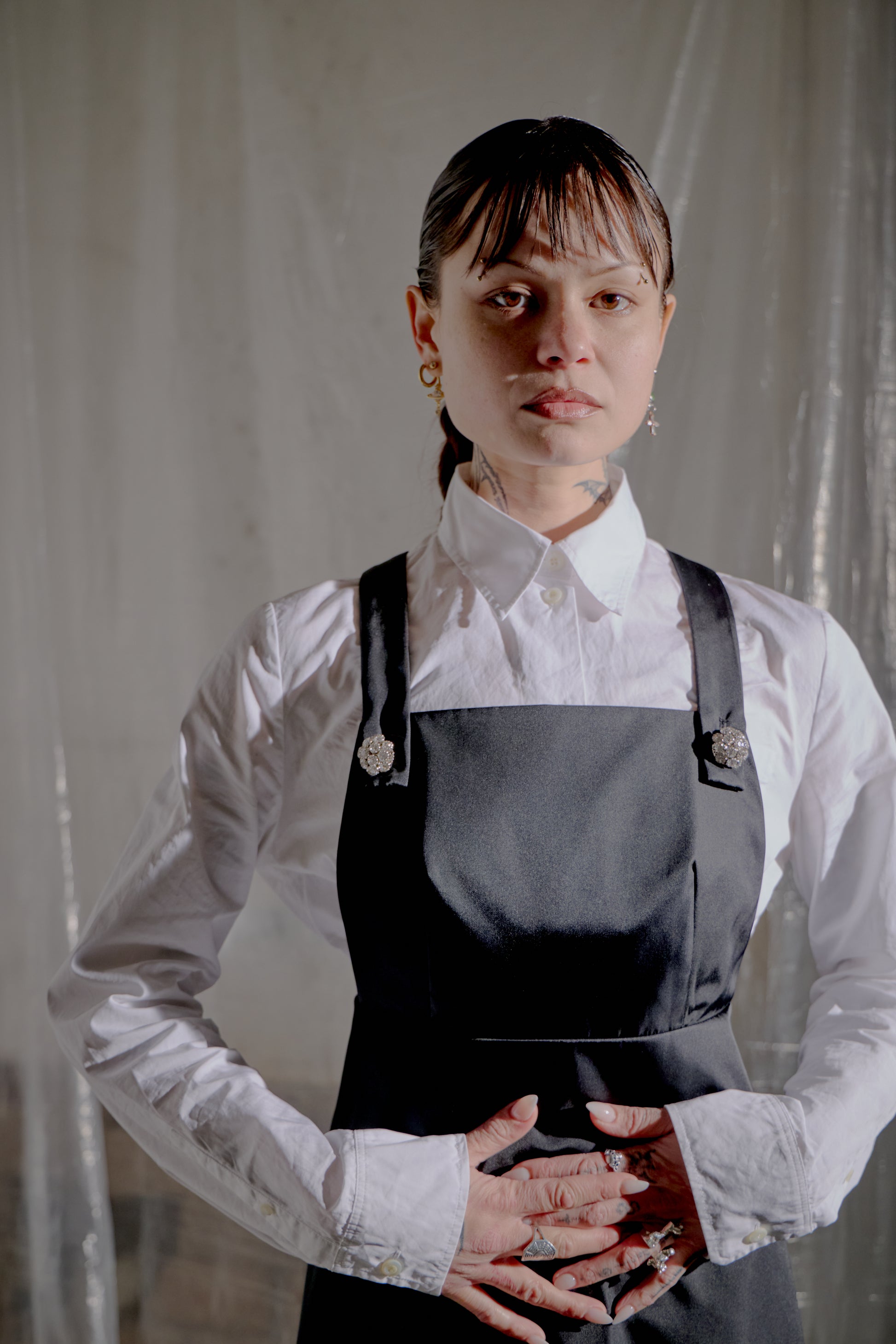 Person wearing a white shirt and grey Prada dress against a plain background