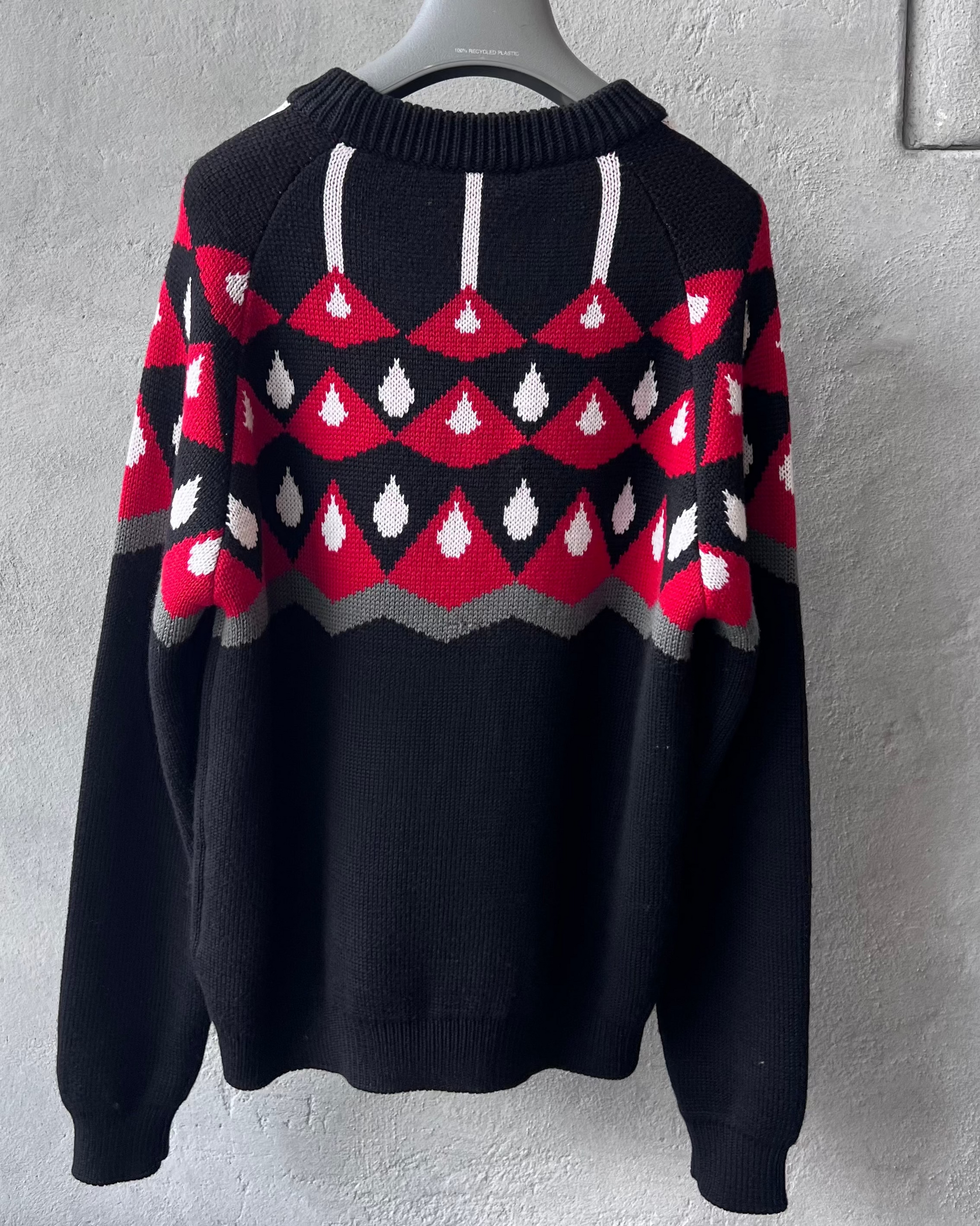 Black Prada sweater with red and white pattern on a gray background