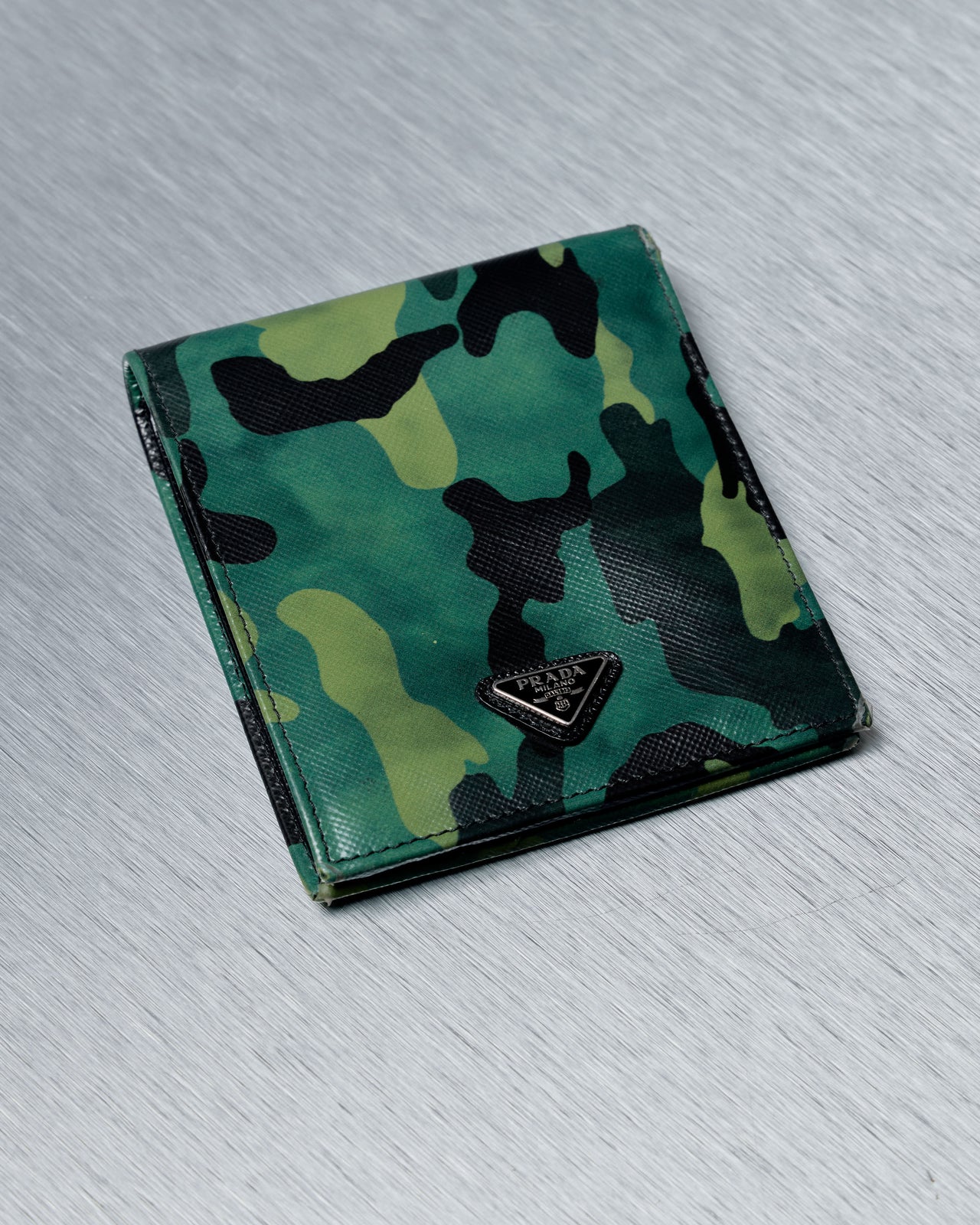 Camouflage-patterned green Prada wallet with a brand logo on a light gray background